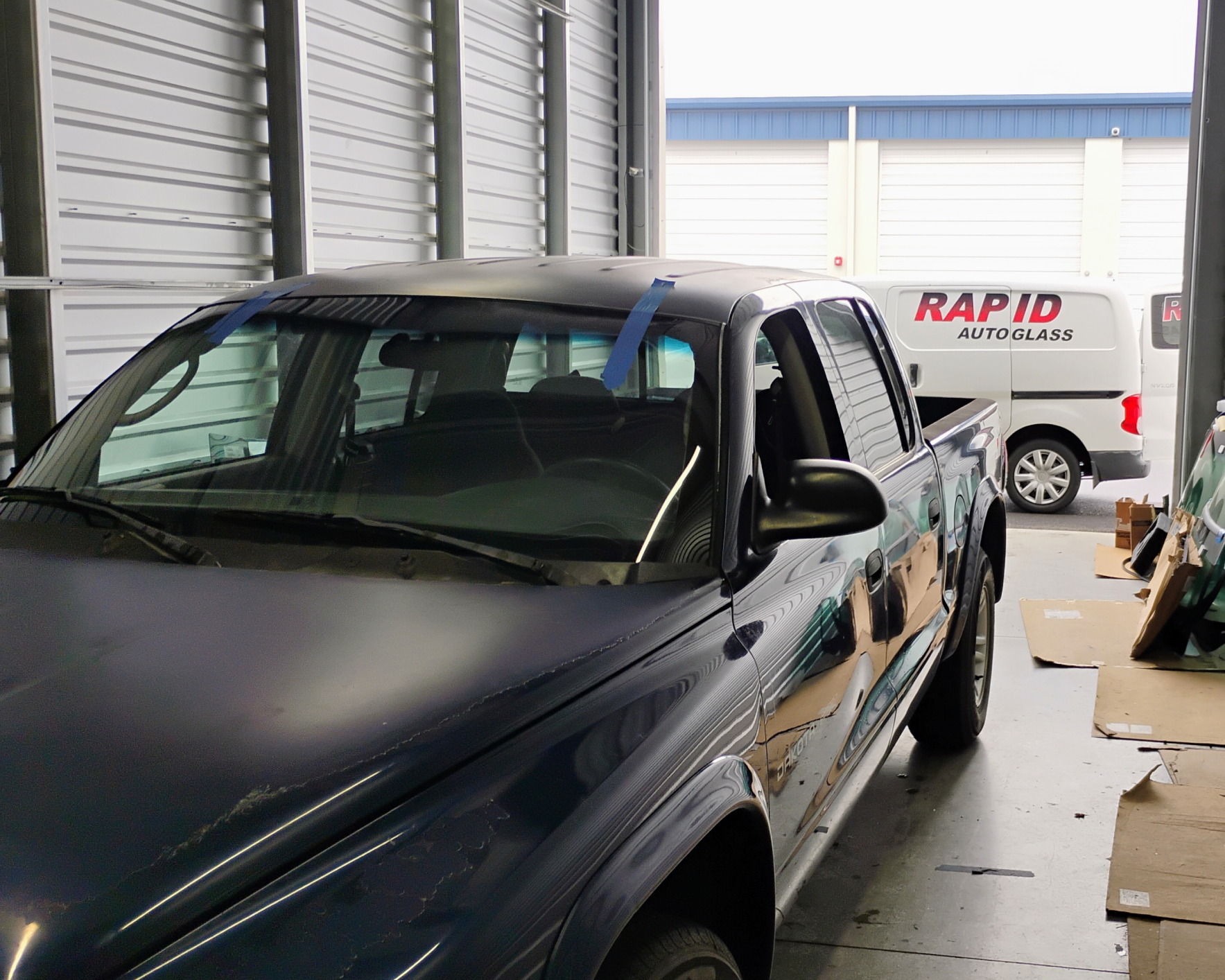 Truck inside garage with service van outside.