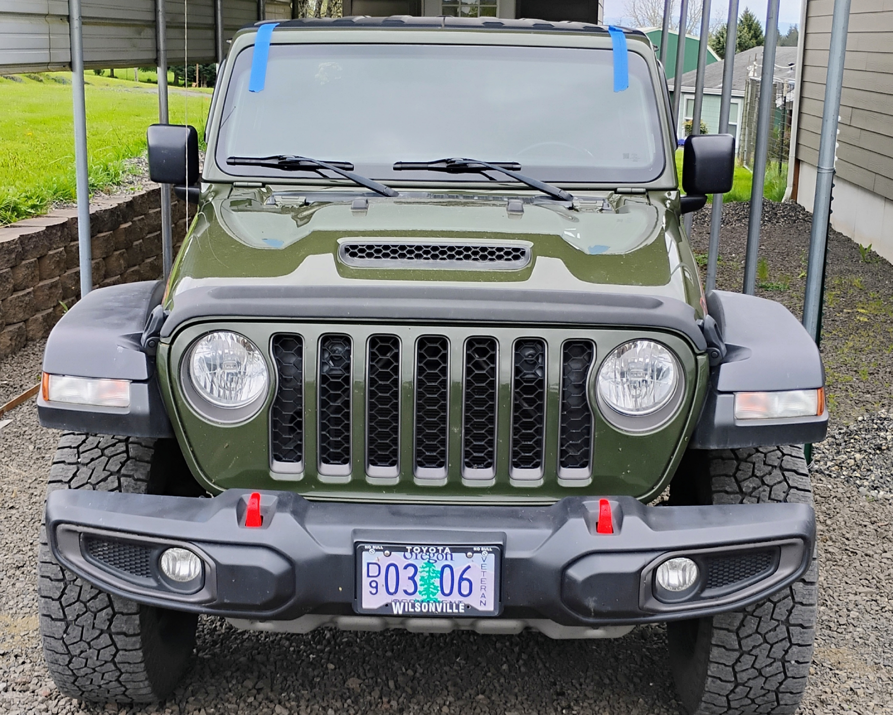 Green Jeep parked under carport.